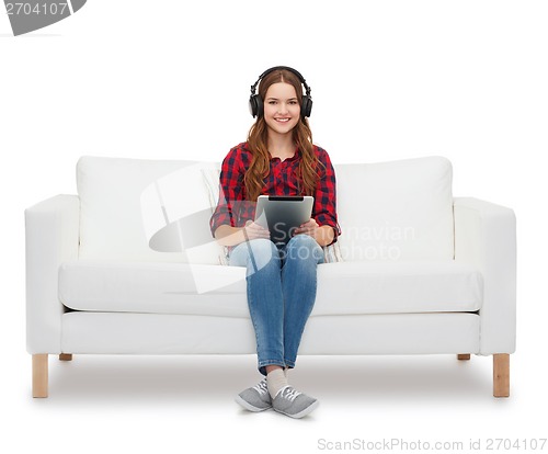 Image of girl sitting on sofa with headphones and tablet pc