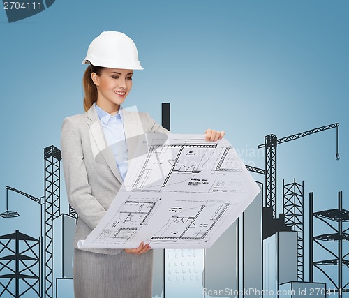 Image of smiling architect in white helmet with blueprints