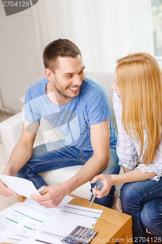 Image of smiling couple with papers and calculator at home