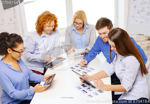 Image of smiling team with table pc and papers working