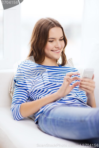 Image of smiling teenage girl with smartphone at home