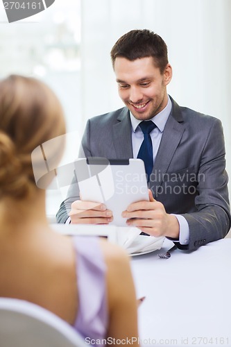 Image of smiling man looking at menu on tablet pc computer