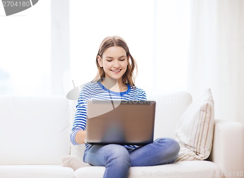 Image of smiling teenage girl with laptop computer at home