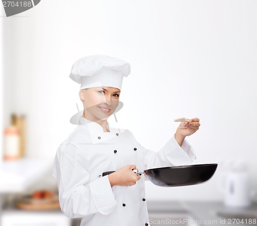 Image of smiling female chef with pan and spoon