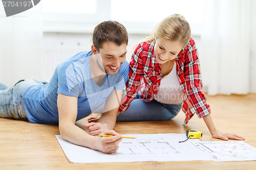 Image of smiling couple looking at blueprint at home