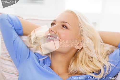 Image of smiling young woman lying on sofa at home