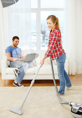 Image of smiling woman with hoover and man with laptop