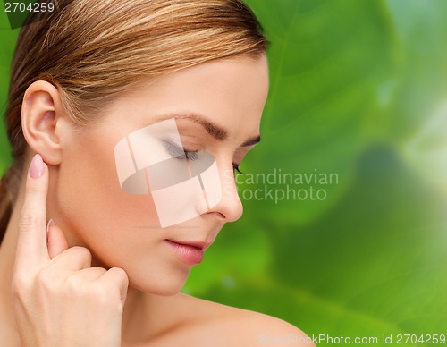 Image of calm woman touching her ear