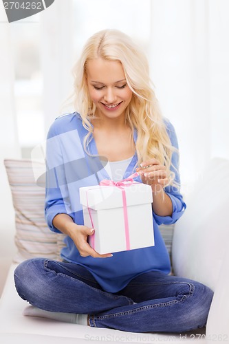 Image of smiling woman with gift box at home