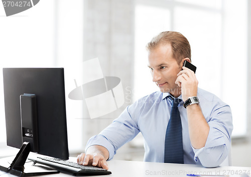 Image of smiling businessman with smartphone in office