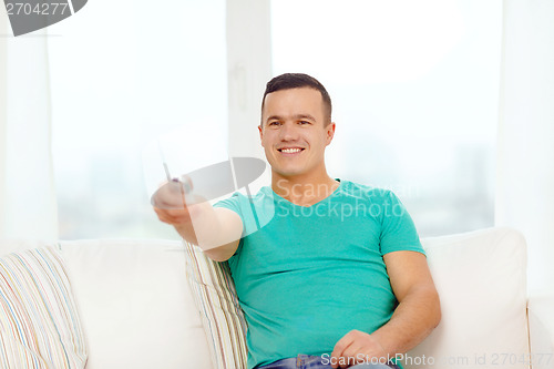 Image of smiling man with tv remote control at home