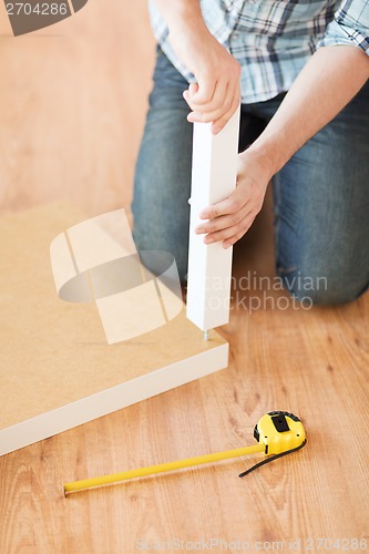 Image of close up of male hands assemblying legs to table