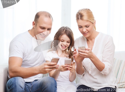 Image of parents and little girl with smartphones at home