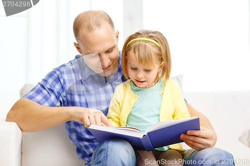 Image of smiling father and daughter with book at home