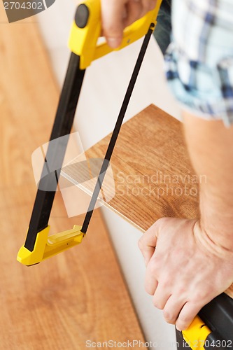 Image of close up of male hands cutting parquet floor board