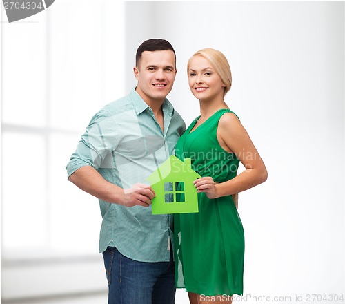 Image of smiling couple holding green paper house