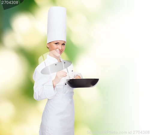 Image of smiling female chef with pan and spoon