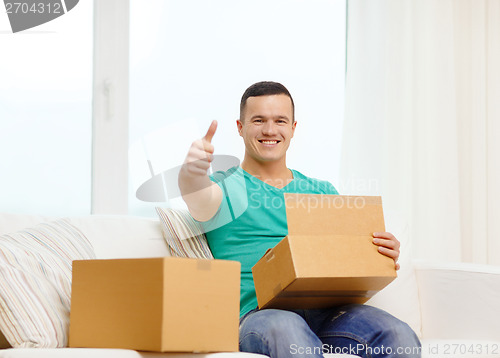 Image of man with cardboard boxes at home showing thumbs up