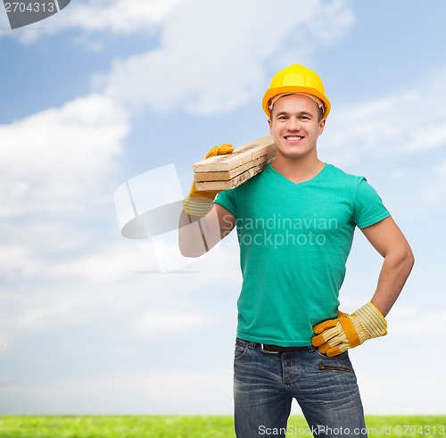 Image of smiling manual worker in helmet with wooden boards