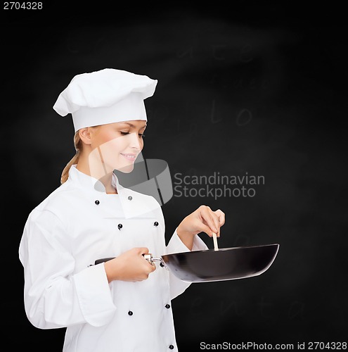 Image of smiling female chef with pan and spoon