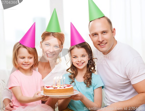 Image of smiling family with two kids in hats with cake