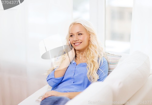 Image of smiling woman with smartphone at home