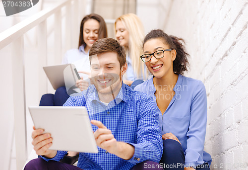 Image of team with tablet pc computer sitting on staircase