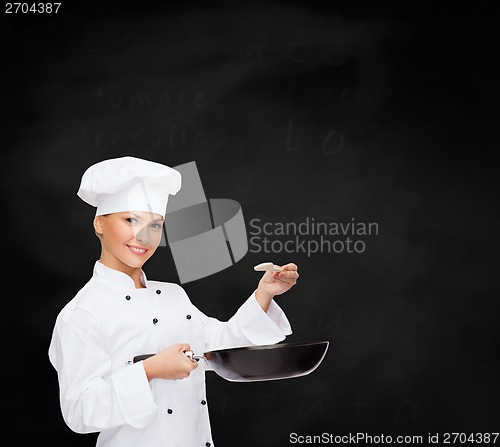 Image of smiling female chef with pan and spoon