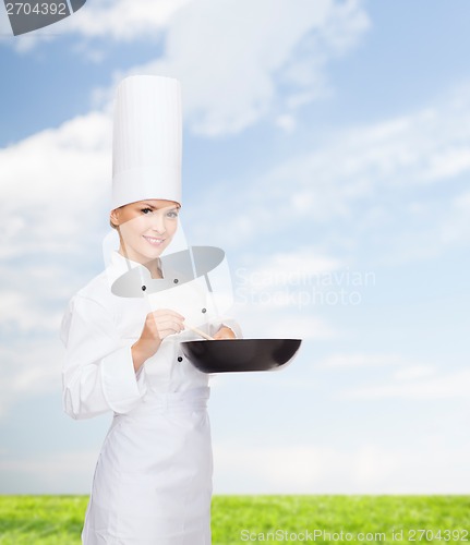 Image of smiling female chef with pan and spoon