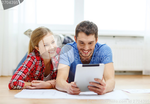 Image of smiling couple looking at tablet pc at home