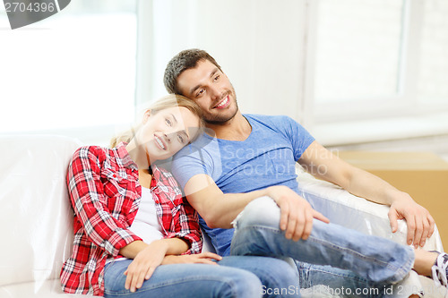 Image of smiling couple relaxing on sofa in new home