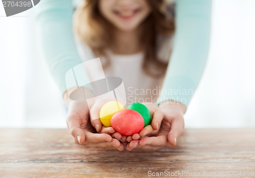 Image of close up of girl and mother holding colored eggs