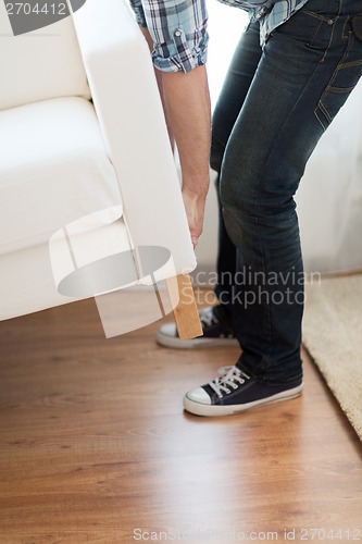 Image of close up of male lifting up sofa to move