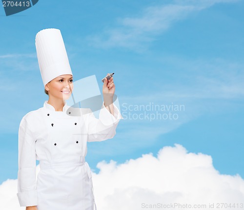 Image of smiling female chef writing something on air