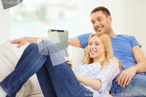 Image of smiling happy couple with tablet pc at home