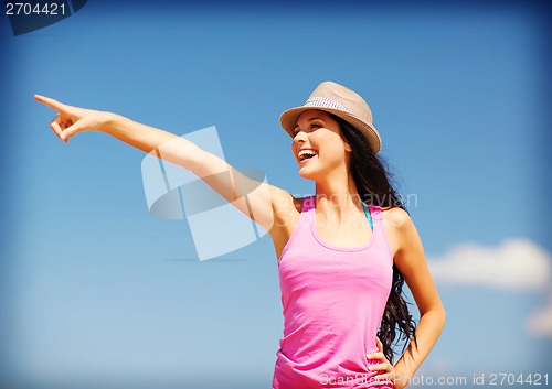 Image of girl in hat showing direction on the beach