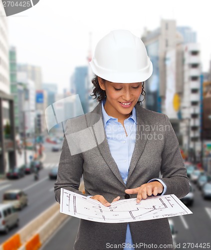 Image of businesswoman in white helmet with blueprint