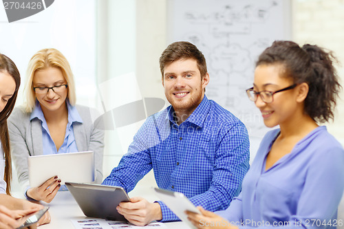 Image of smiling team with table pc and papers working