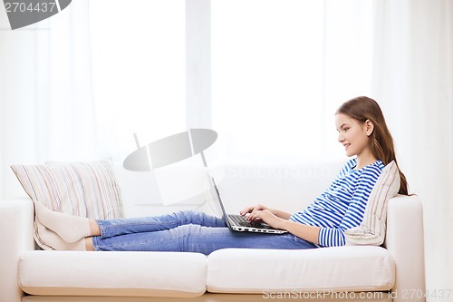 Image of smiling teenage girl with laptop computer at home