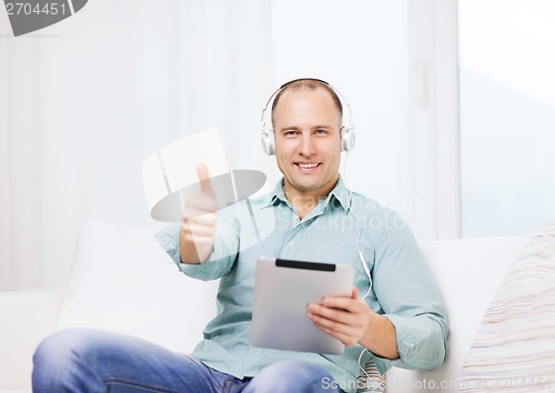 Image of smiling man with tablet pc and headphones at home