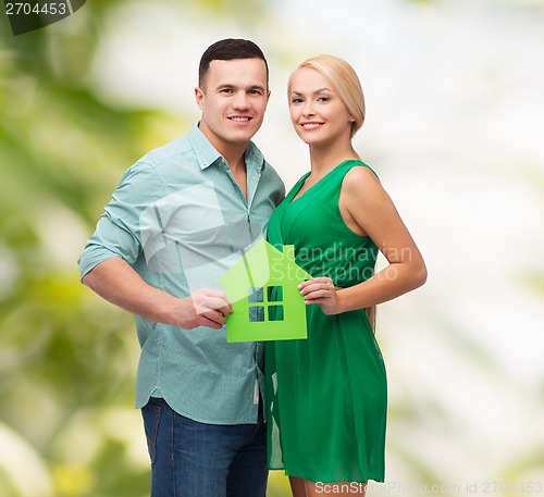 Image of smiling couple holding green paper house