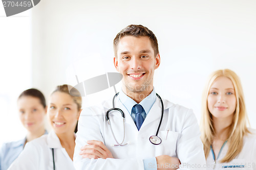 Image of smiling male doctor in front of medical group