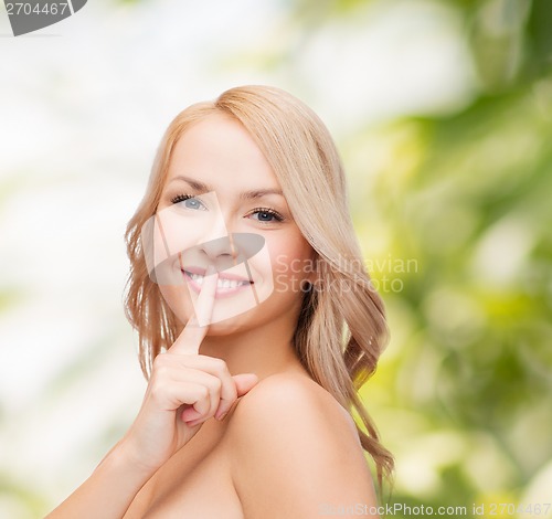 Image of beautiful young woman pointing finger to lips