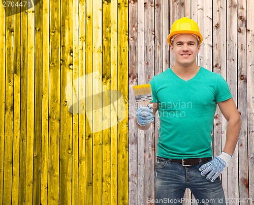 Image of smiling manual worker in helmet with paintbrush
