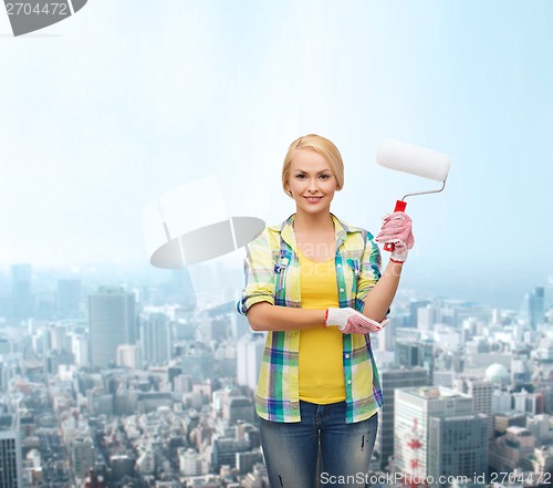 Image of smiling woman in gloves with paint roller