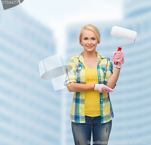 Image of smiling woman in gloves with paint roller