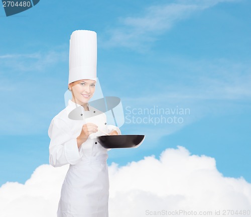 Image of smiling female chef with pan and spoon