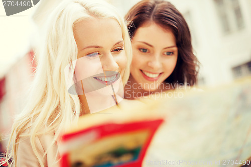 Image of beautiful girls looking into tourist map in city