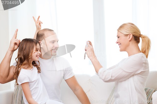 Image of happy mother taking picture of father and daughter