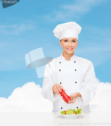 Image of smiling female chef with preparing salad